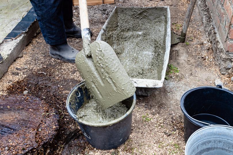 Construction worker using a wheelbarrow to transport concrete